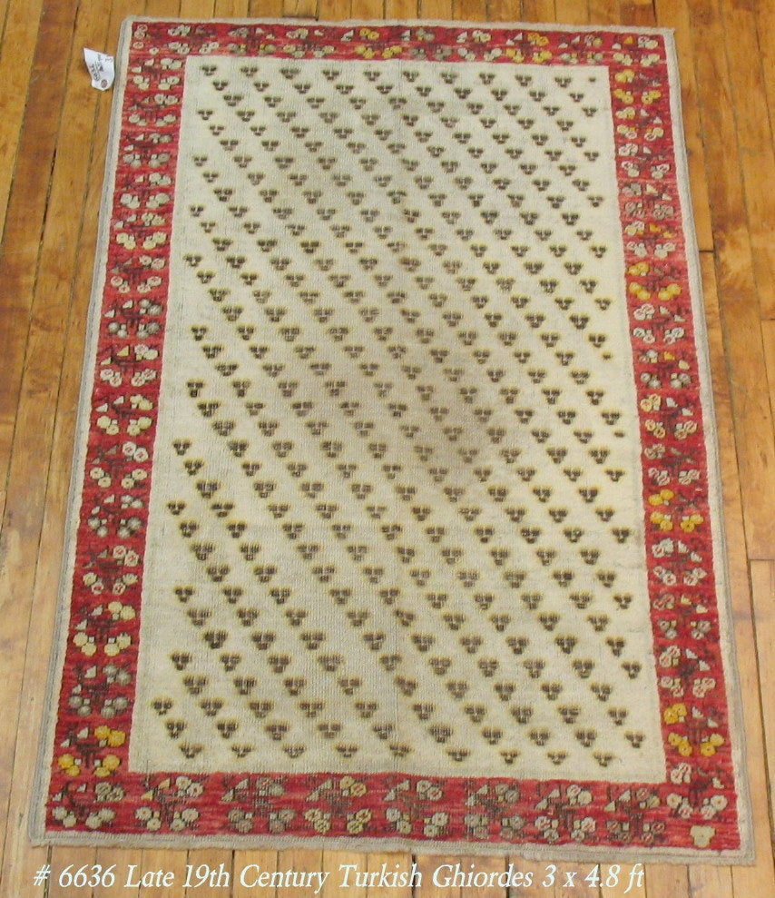 Late 19th century antique Turkish Ghiordes rug. Ivory ground, small repetitive field surrounded by a floral red border

3' x 4'8''