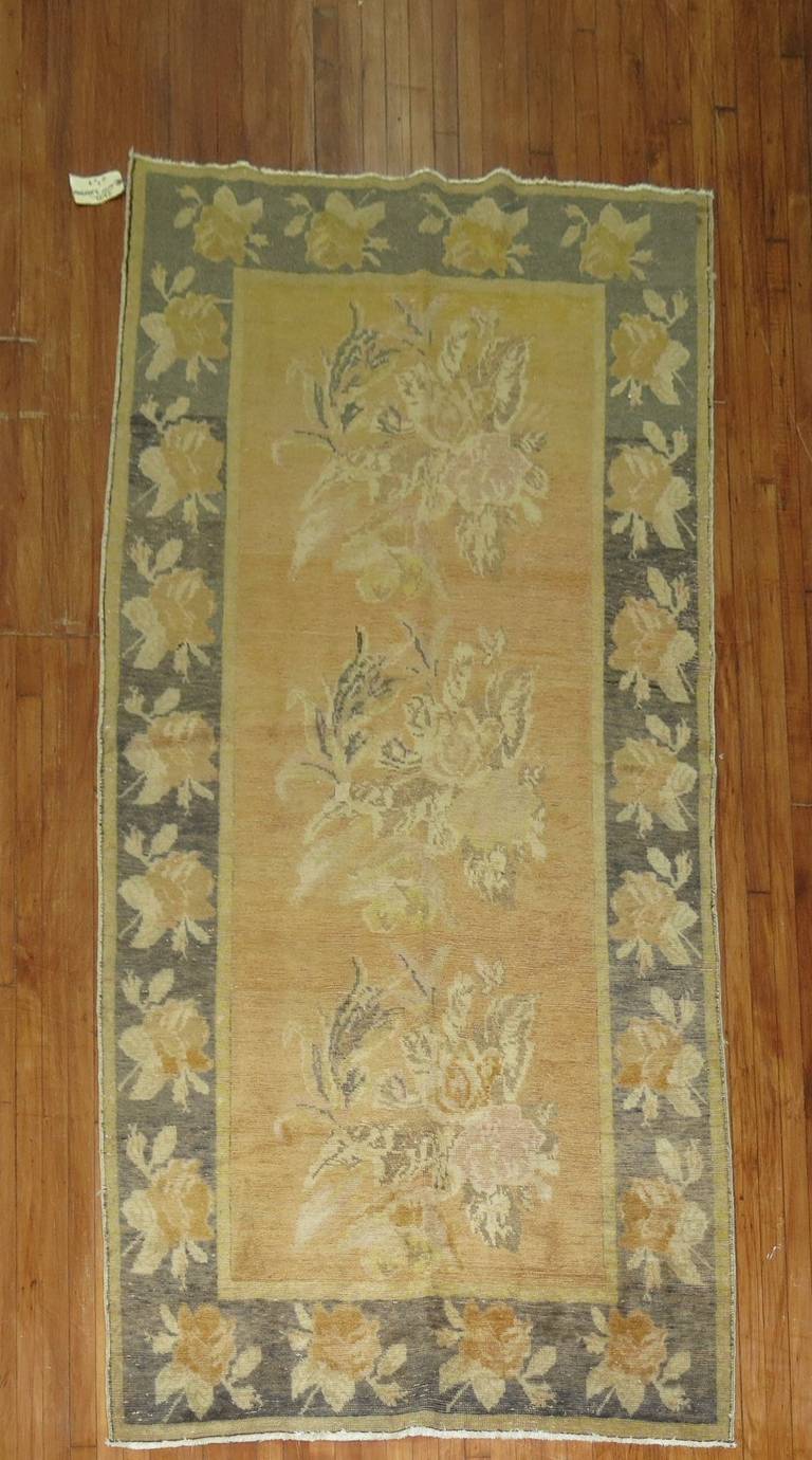 A classic Karabagh rug with flowers running through an apricot colored field and charcoal colored border.