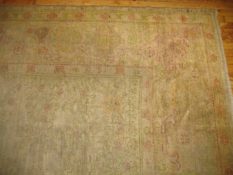 A large size late 19th century antique Turkish Oushak rug with a silvery gray field, accents in green, gold, raspberries.