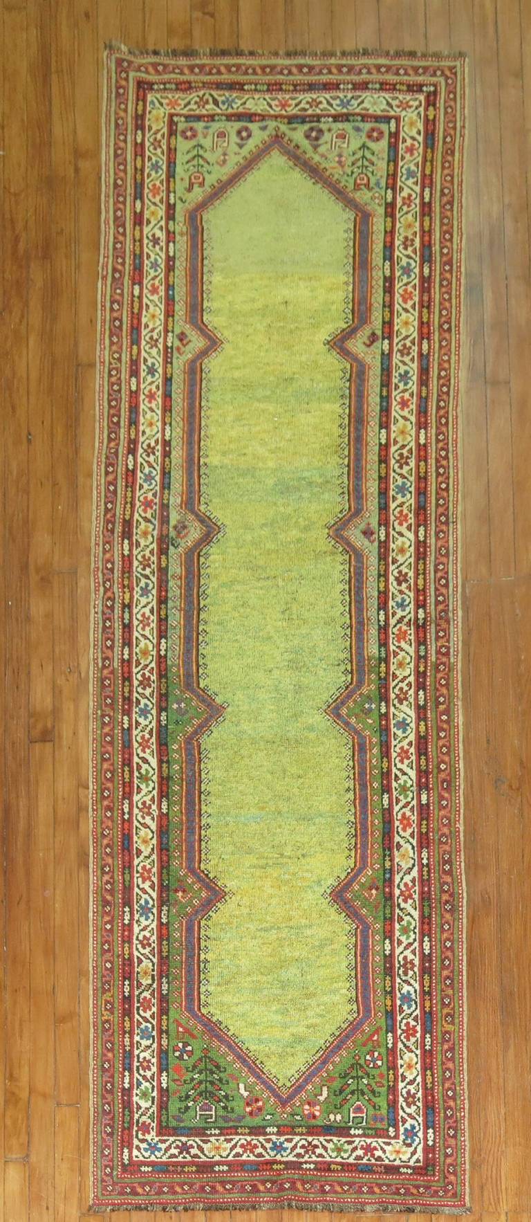 A fascinating early 20th century Persian runner with an open lime green field.