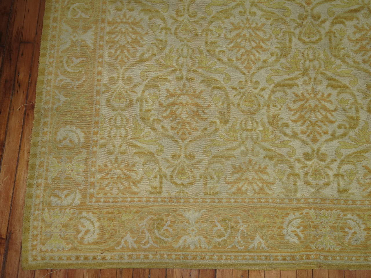 A room size Spanish rug. Ivory field, accents in green and orange.