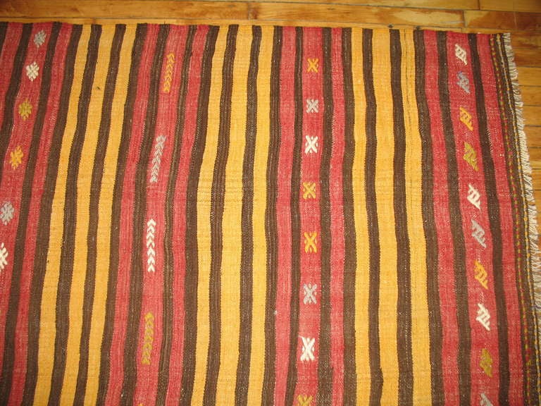 A room size midcentury handwoven striped Turkish Kilim in yellows, rust and brown accents,

circa mid-20th century, measures: 7'9” x 10'9”.