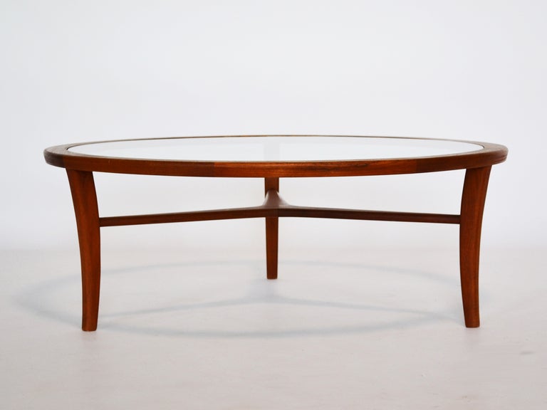 This handsome teak Danish table has a glass top that displays the sculptural quality and fine joinery of the legs and stretchers. It is a perfect example of the refined woodworking and restrained elegance that are hallmarks of Danish design