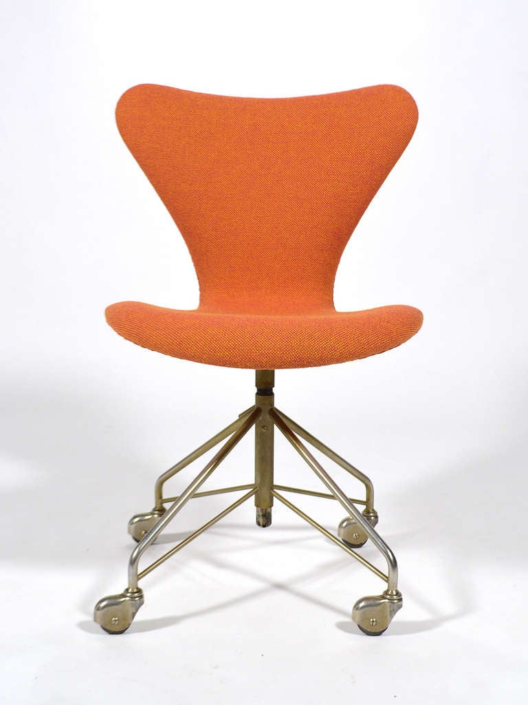 This lovely early example of Arne Jacobsen's sevener chair has a swivel function, adjustable height and a four star task base. It is upholstered in Hallingdal 65 fabric (designed by Nanna Ditzel) in a two-tone orange colorway.