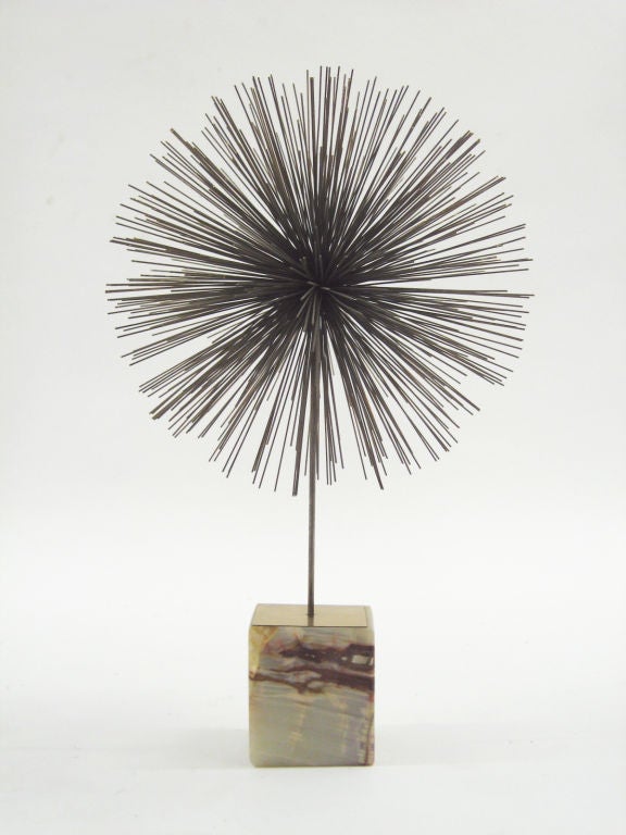 A wonderful Jeré sculpture, this piece is a three dimensional version of the burst design in a dandelion form supported by a single rod on an onyx base. In very good original condition, it’s signed on a brass cover-plate on the base.