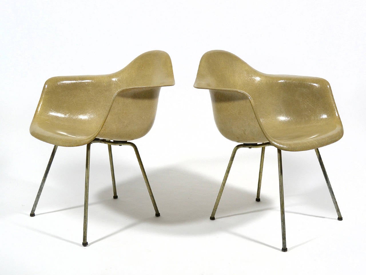 These very early armchairs by Charles and Ray Eames have all the details that collectors look for and which distinguish them so greatly from later production and especially re-issued chairs. They have the uncommon greige color and solid X bases of