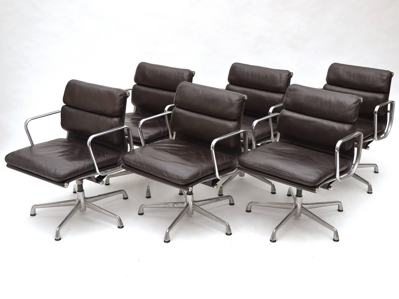 This beautiful set of Eames soft pad chairs is in excellent original condition. They have rich brown/ black leather upholstery the color of black coffee, swivel, and tilt function. The arms, which commonly show wear and losses to the protective