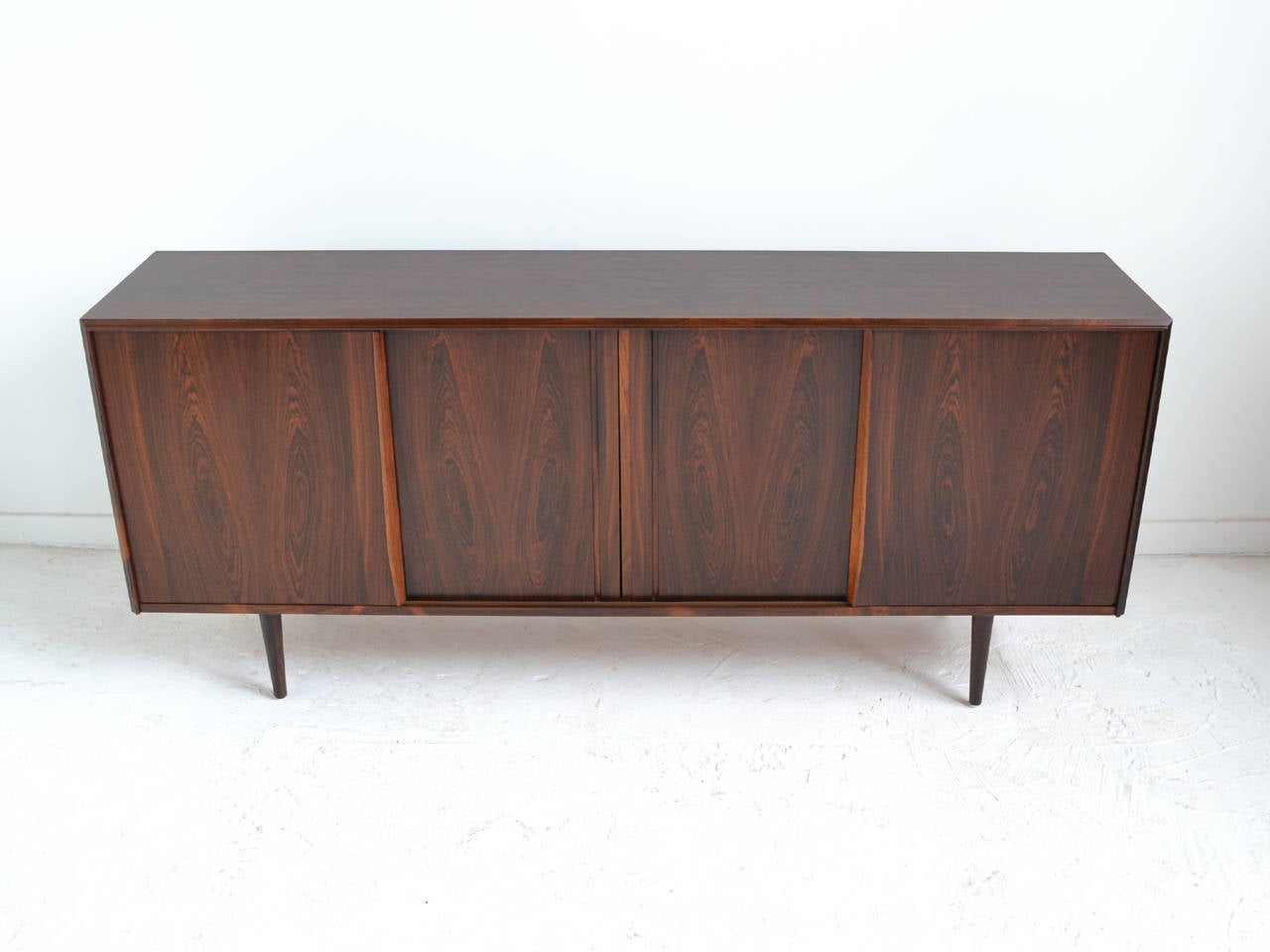 This spectacular credenza clad in rich, highly figured Brazilian rosewood is loaded with subtle details. The fine craftsmanship is evident everywhere you look: the sculpted edge and door pulls, the dovetailed drawers and mirror-lined cabinet. The