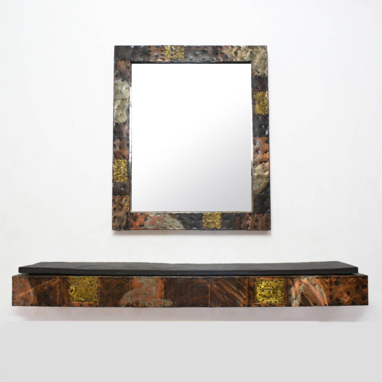 A fantastic early example, this striking wall-mounted console and matching mirror by Paul Evans is from his copper, bronze and Pewter patchwork series. The hammered and heavily worked squares of copper and bronze give an architectural geometry which