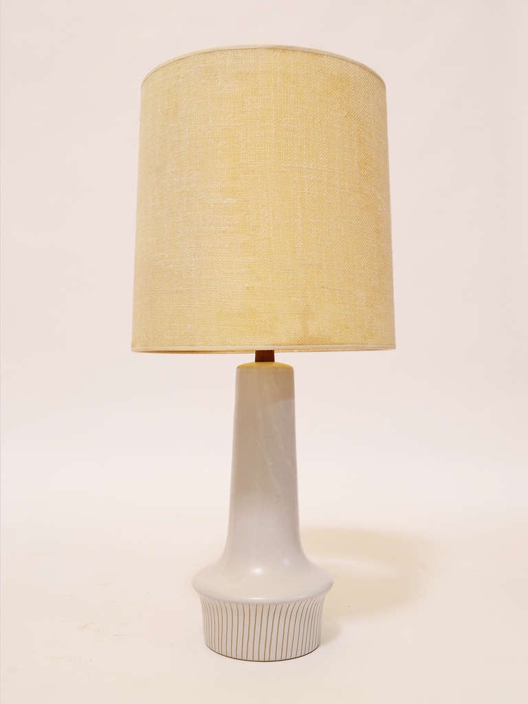 This attractive model 194 table lamp by Gordon and Jane Martz features their signature eggshell white glaze decorated with subtle sgraffito lines on the bottom of the base. It has a walnut neck and the original walnut finial. It is hand signed at