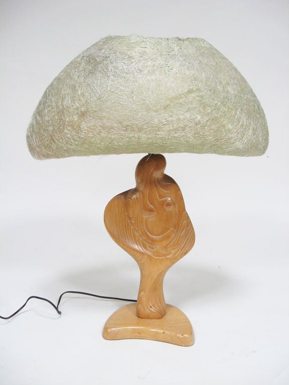 This sensuous table lamp executed in wood is an abstracted female figure. The form works in perfect symphony with the natural wood grain. It still has the original spun fiberglass shade, but the lamp base is so striking it would look as beautiful