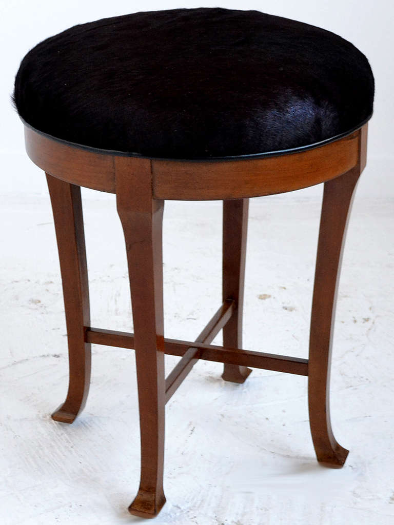 This elegant mahogany stool features tapered legs with flared feet. It is upholstered in a dark, rich hair-on-hide leather.