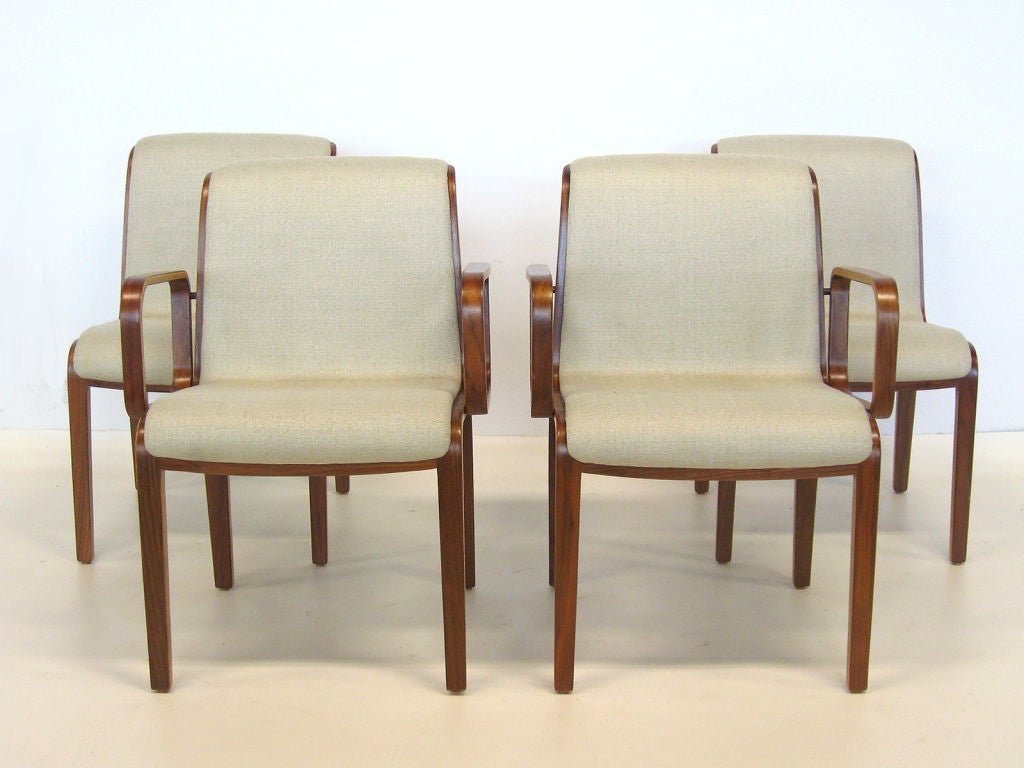 Four Bill Stepehens chairs, two arm and two side, are newly upholstered in a nicely textured ecru colored fabric. They have also been refinished, exposing the natural beauty of the laminated wood used to create the elegant chair frame and arms.