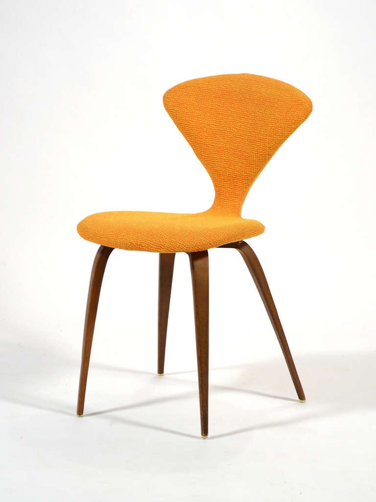 This uncommon Cherner side chair features an upholstered seat and back in an orange and gold fabric adding an extra measure of comfort. Norman Cherner developed this chair for Plycraft as a redesign of the Nelson pretzel chair.
