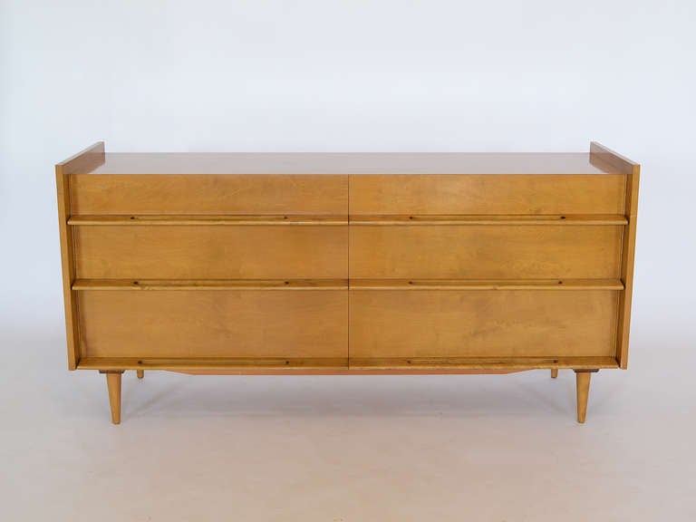 A beautiful design by Edmond Spence, this long, low chest has great lines. The sides are raised, integrated sculptural drawer pulls and the cabinet is perched atop slender conical legs. 

Also available is a matching dresser and pair of