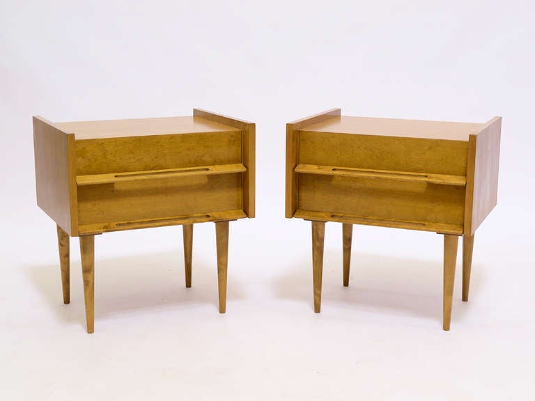 Light in color, light in scale, this handsome pair of nightstands by Edmond Spence are perched on long tapering legs, have raised edges and great integrated sculptural drawer pulls. They work perfectly at the bedside and also as end tables.