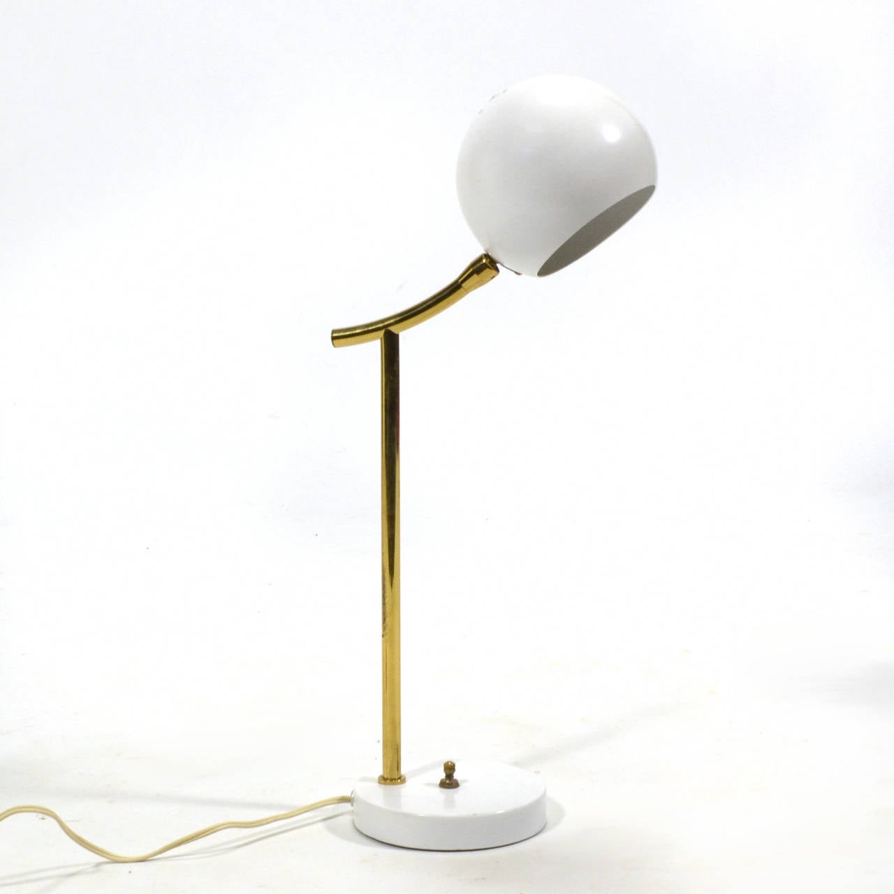 Eine kleine Lampe ist perfekt für den Schreibtisch oder den Tisch. Dieses wunderbare Design von Nessen ist sowohl verspielt als auch raffiniert. Ein weißer Sockel und Kopf sind durch einen Messingstiel oder -hals verbunden, der sowohl Umgebungslicht