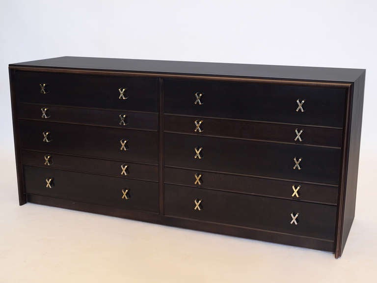 This classic 10 drawer chest by Paul Frankl features the signature X shaped brass pulls and refined design. It has just been refinished in a rich brown-black and is marked inside the drawer.

Also available is a matching pair of nightstands/ end