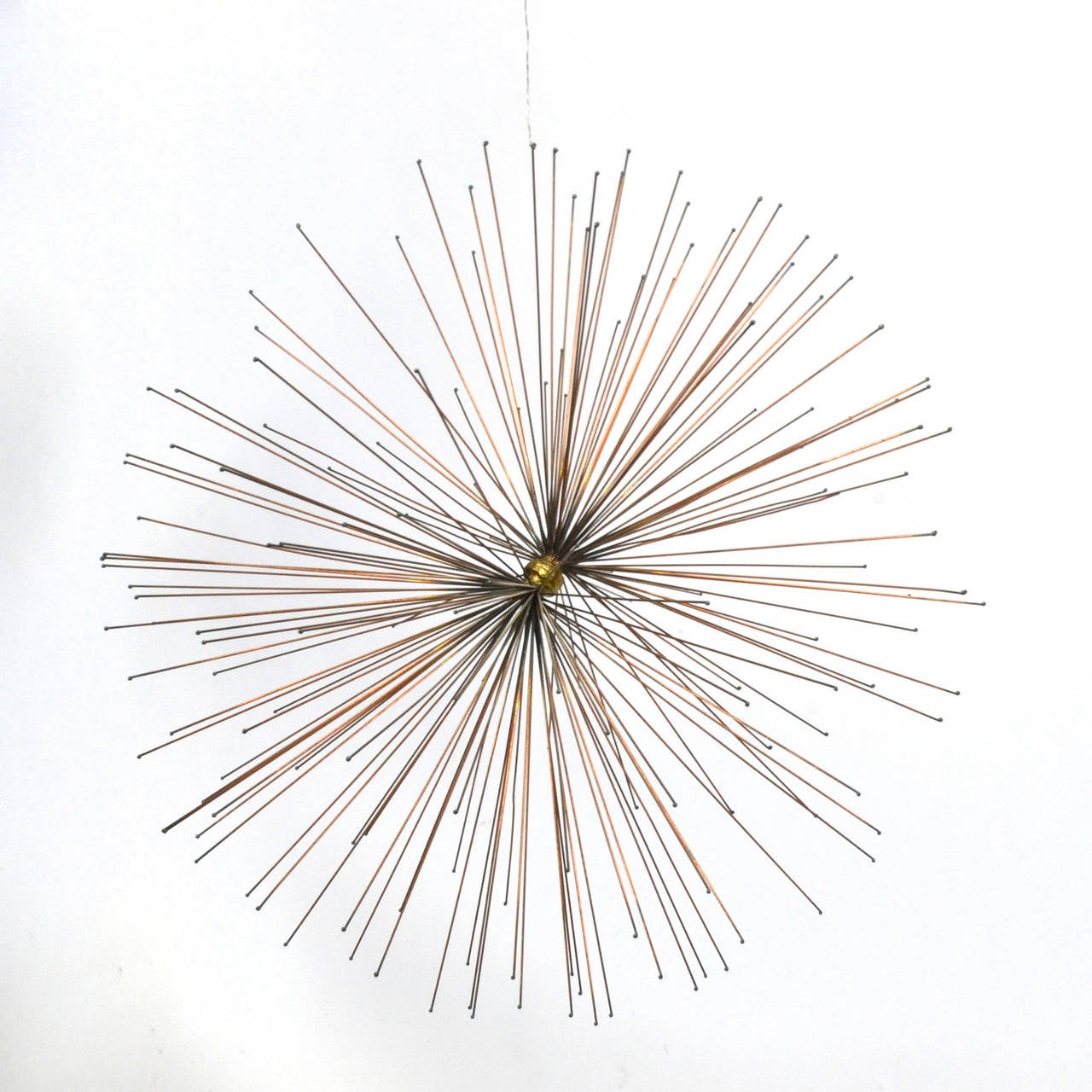 This beautiful sculpture by Thomas Hibben is a starburst form designed to hang from above like a mobile activating space near the ceiling seldom utilized. The bronze rods all have a small detail on the tips and gather in the center in a welded mass