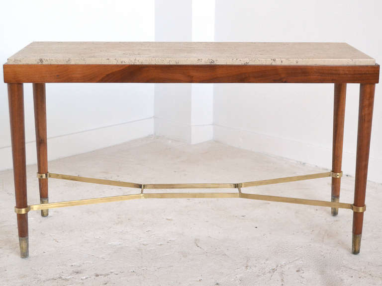 A handsome and petite table of Walnut, this piece would work well behind a sofa, as a console table in an entry, or as an occasional table. It has brass feet and stretcher between the legs, the top is of travertine marble.