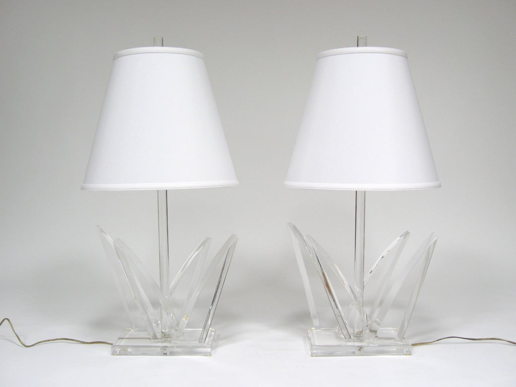 This striking matched pair of Lucite table lamps by Van Teal have style to spare. They each have four angular elements on the base and a round central stem that conceals the wire. They are each hand signed on the base.

The lamp bases each