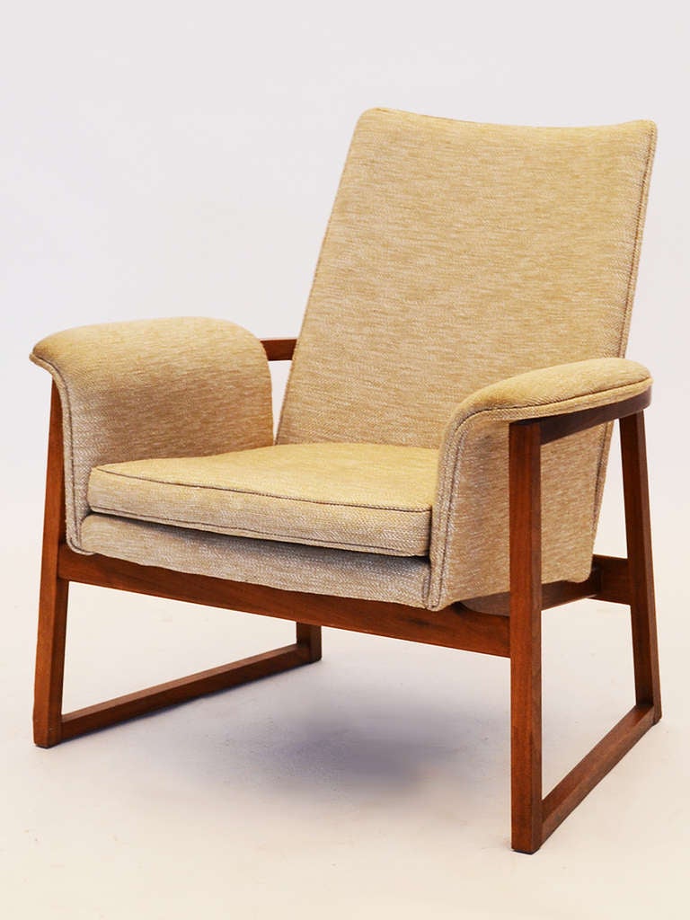 This lounge chair by Jens Risom has an upholstered body that is cradled in a walnut frame with a sled base. The clear delineation of the two elements is characteristic of many Danish designs. Though Risom has lived and worked in the US from 1939, he