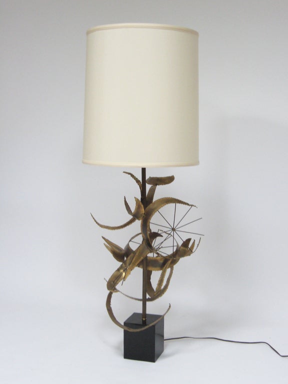 This dramatic large-scale table lamp by  Bijan of California for Laurel titled “Setarrah”. It has a base that is a powerful metal sculpture surrounding the central stem above the black lacquered wood base. It is a compelling piece and an interesting