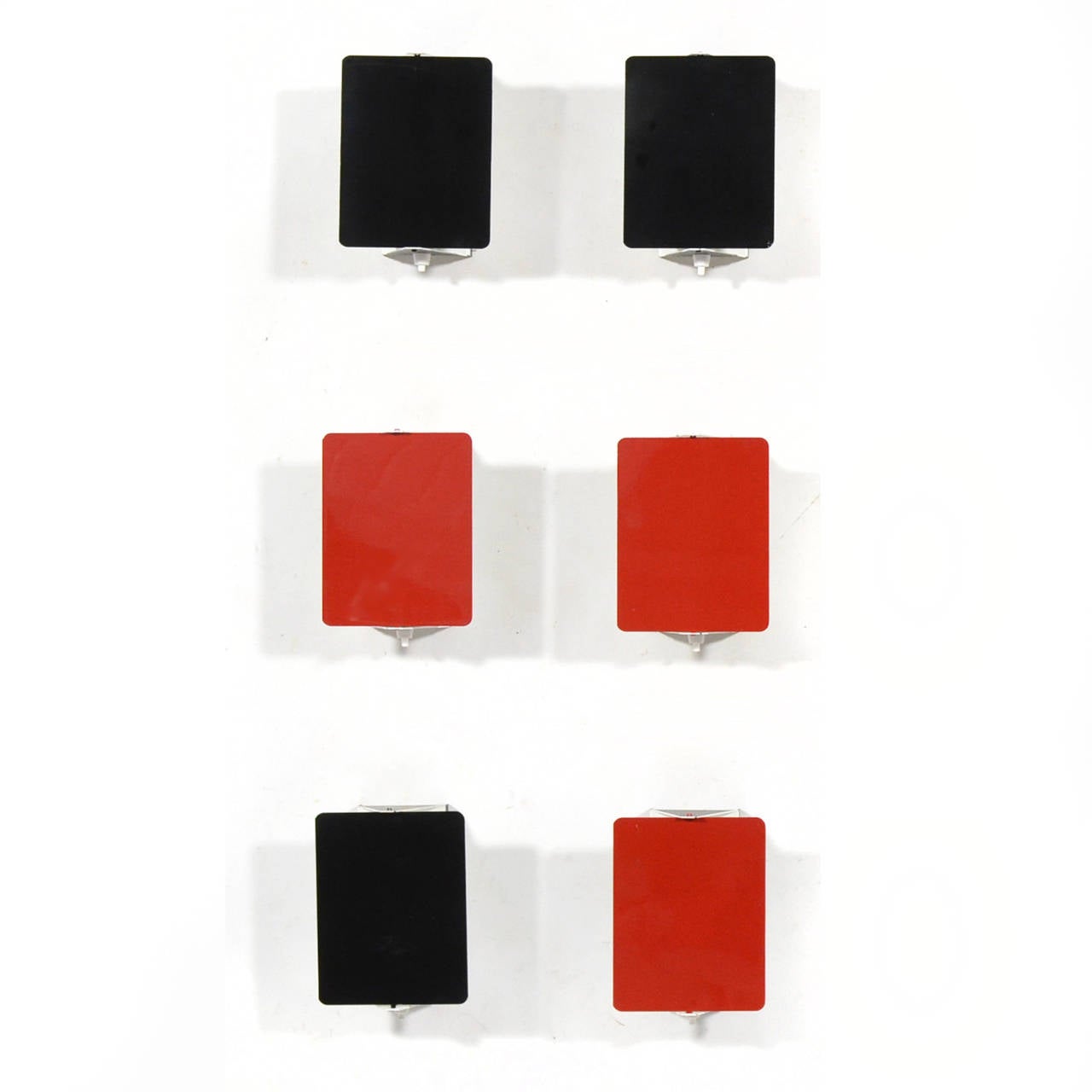 This set of six Perriand wall sconces features three red lamps and three black. A brilliant minimal design by Perriand, the pivoting shade shields glare and directs the light. The lamps may be used vertically or horizontally and can be arranged in