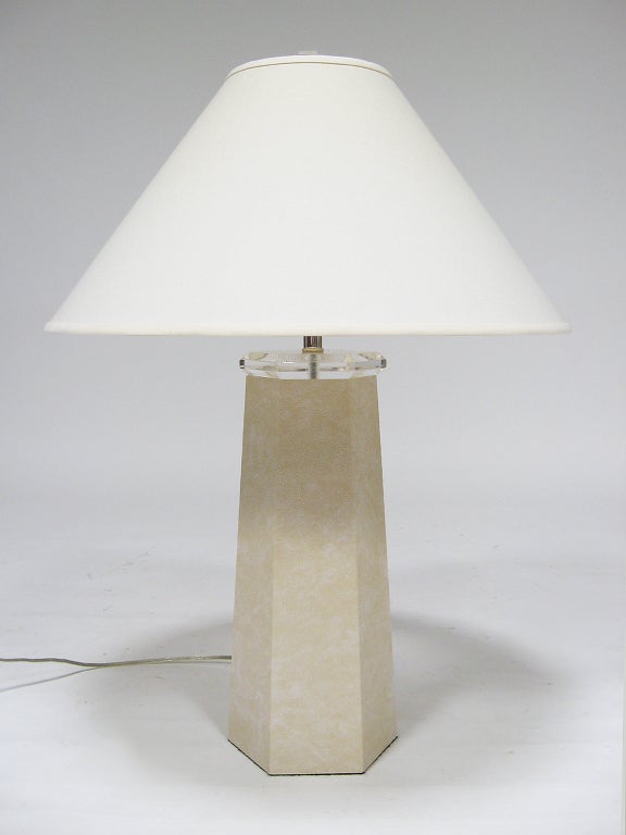 This table lamp is in the manner of Karl Springer with a hexagonal base covered in faux lizard skin and topped with lucite. The lamp is in very good original condition and retains the original linen shade and lucite finial.
