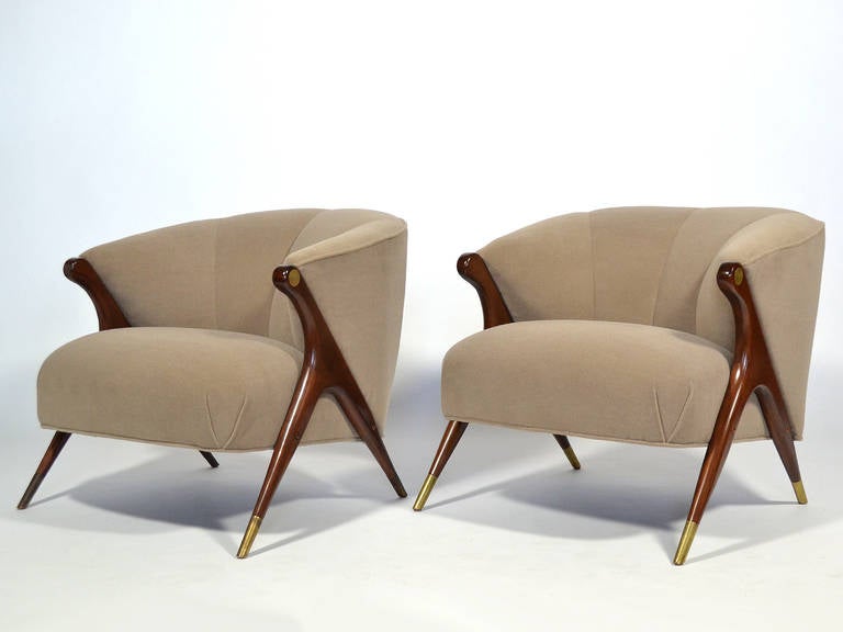 These two dramatic club chairs by California furniture company Karpen have fantastic lines. The barrel shaped body is supported by a rich wood frame that has a Gio Ponti-like dynamism. They have brass sabots and a round brass medallion on the