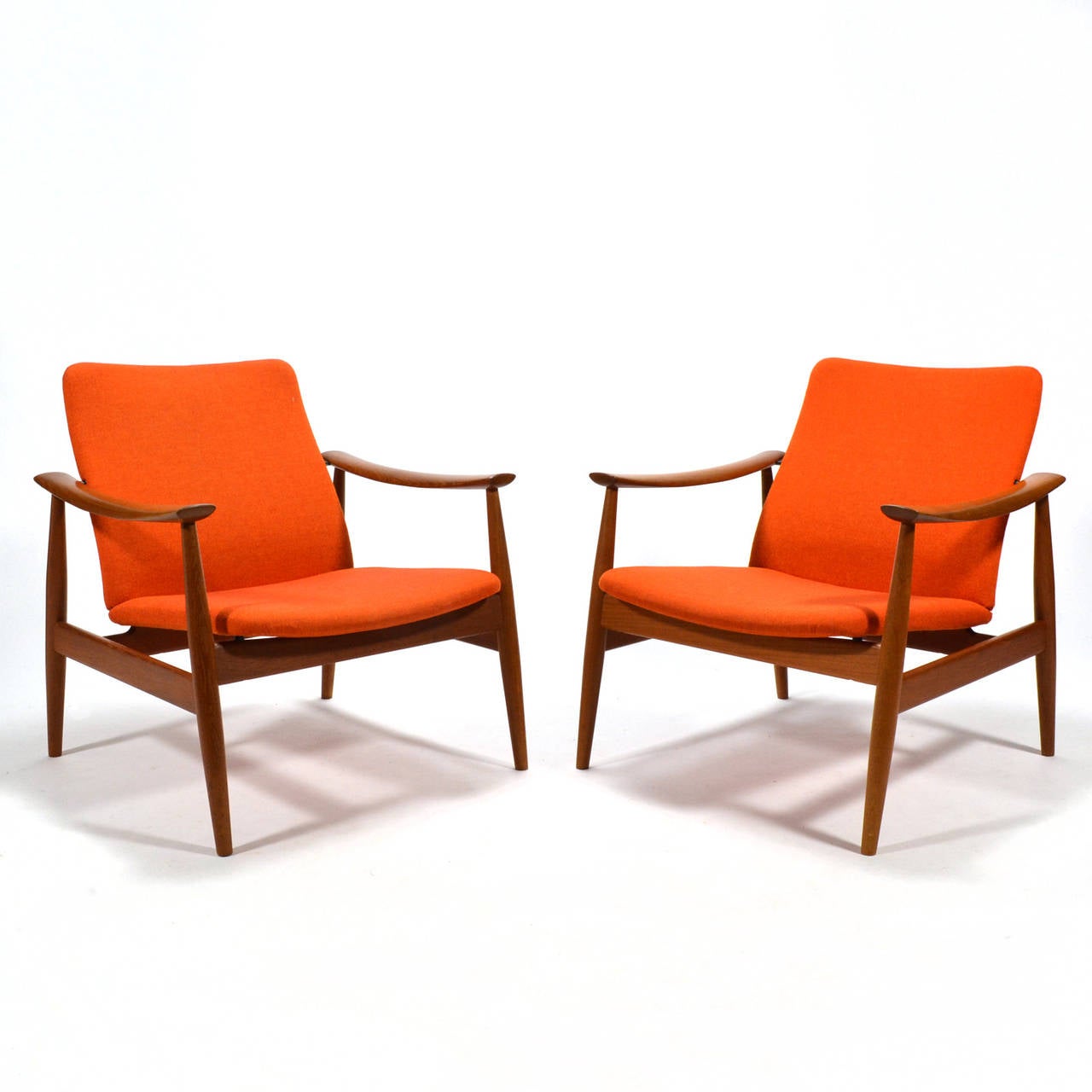 Designed in 1961 for France & Søn, this exquisite pair of model 138 lounge chairs by Danish master Finn Juhl have sculpted frames of teak supporting a 