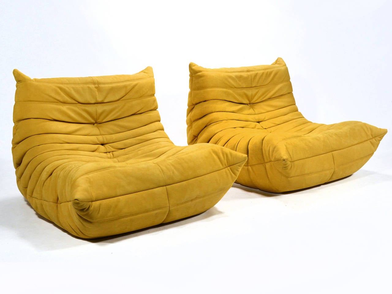 Designed in 1973 by Michel Ducaroy the Togo reflects the soft, relaxed organic design sensibility of its era. Supremely comfortable, the lounges have a core of multiple density foam wrapped in a quilted cover. This pair is upholstered in a rich