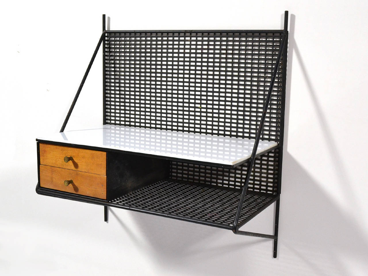 Perfect for almost any space, this wall-mounted shelf by Paul McCobb has two metal shelves, one with a vitrolite glass top, and two small drawers. The combination of iron rod and metal mesh give it a great linear, graphic quality.