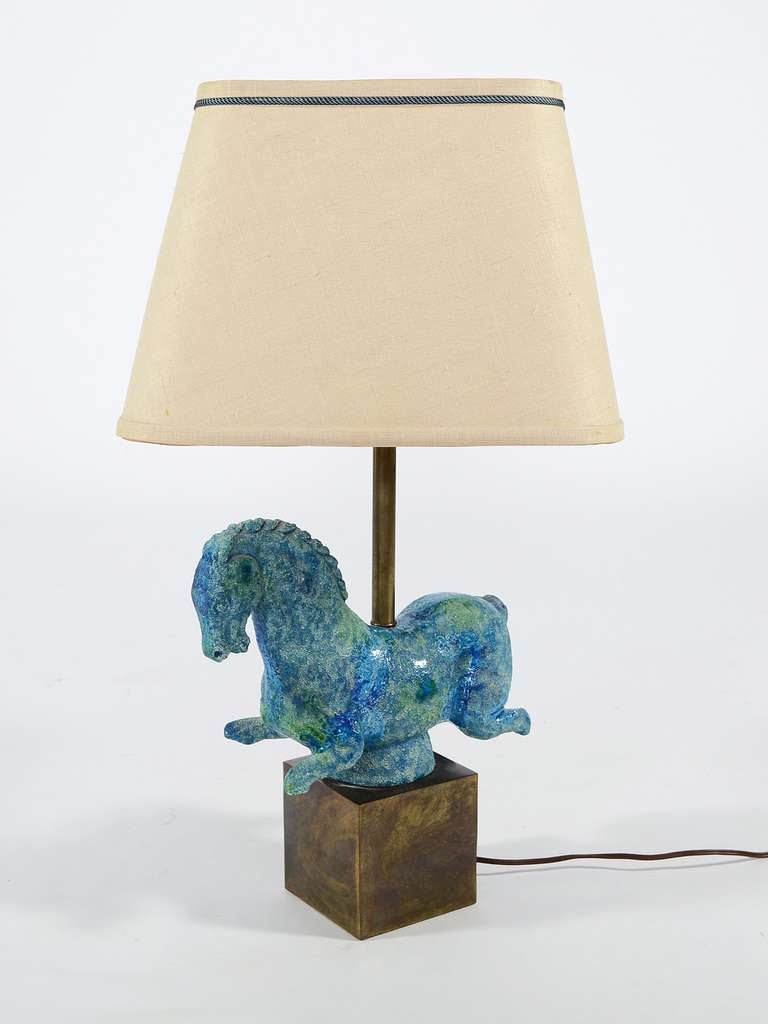This lovely table lamp has a base of brass with a fantastic ceramic horse sculpture which references sculptures from antiquity with partially missing limbs. The blue horse has a most wonderful texture and the distinctive 