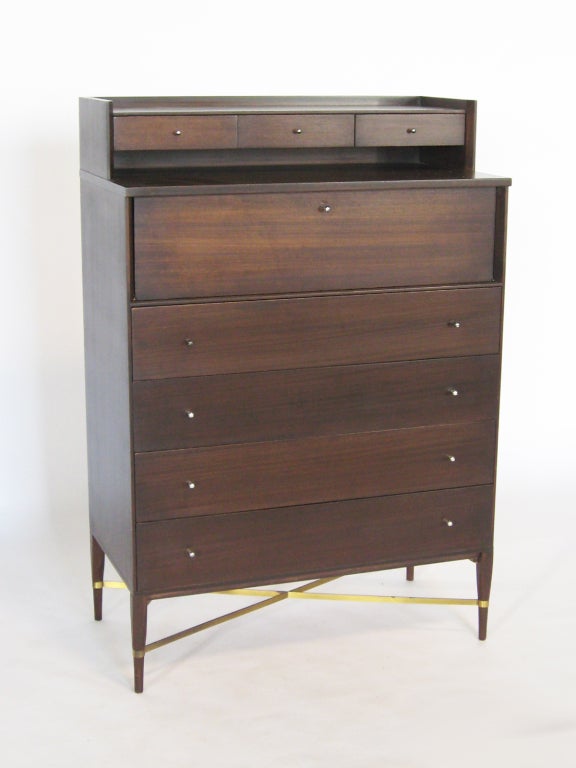 In our opinion one of Paul McCobbs most handsome and desirable designs is this model 1013 gentleman's dresser from the Calvin group. Elegant and stately, it is loaded with refined details. A bank of three shallow drawers floats above a drop front