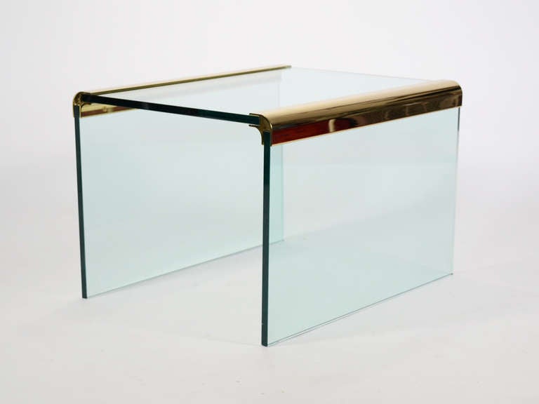 A highly refined minimal aesthetic and extraordinary craftsmanship mark the designs of Leon Rosen created by Pace. This end table employs a beautiful brass connector which joins the thick sheets of glass which make up the top and legs. This example