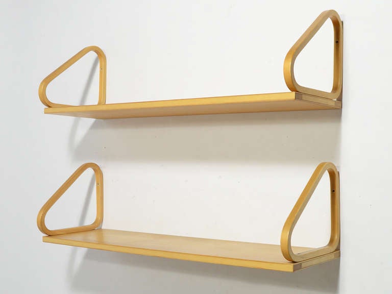 A brilliant design by the Finnish master Aalto, these shelves attach to the wall with laminated birch brackets which also function as bookends. The wood has mellowed to a beautiful honey color only achieved with age.

A third shelf is also