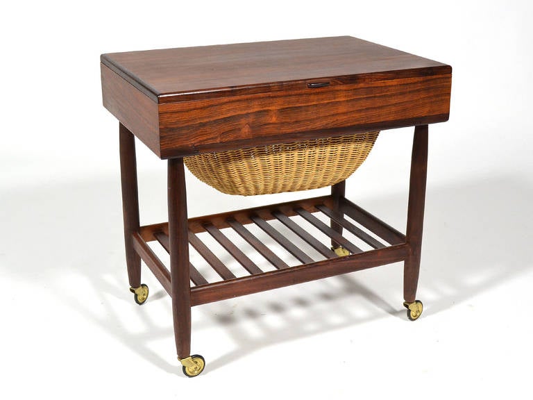 This little sewing table by Ejvind Johansson for FDB Møbler is handsome and useful. Clad in beautiful rosewood, the top opens to a storage compartment and the wicker basket slides out from below. The scale allows it to also serve as a side or