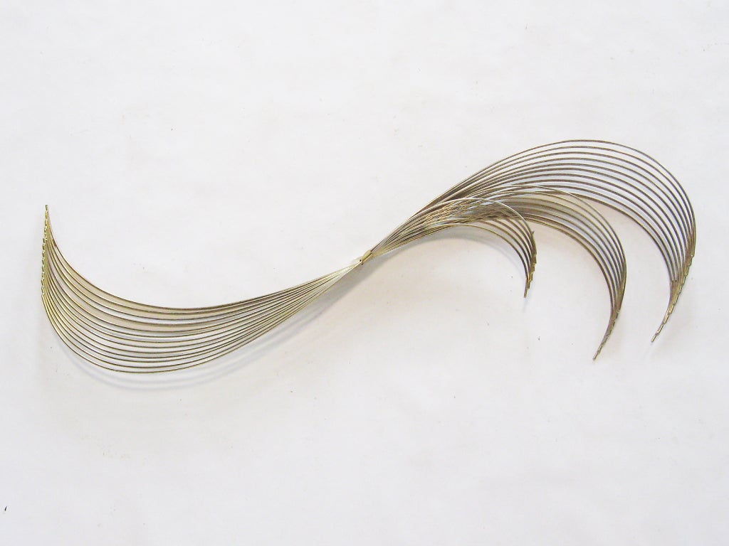 This wall sculpture from the Jere studio consists of a bundle of brass wire rods formed into a curvatious wave or 