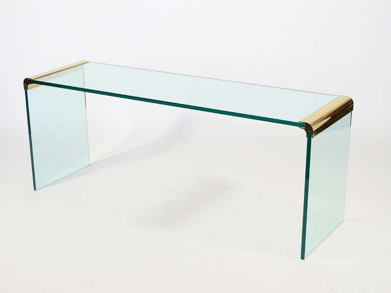 A highly refined minimal aesthetic and extraordinary craftsmanship mark the designs of Leon Rosen created by Pace. This console table employs a beautiful brass connector which joins the thick sheets of glass which make up the top and legs. The size