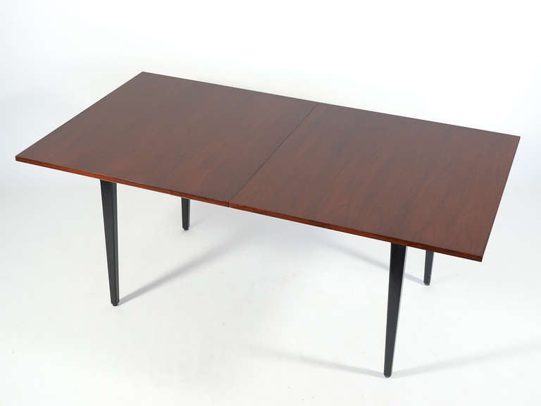 A design of subtle beauty, this rare dining table by George Nelson has a top of rich rosewood supported by tapered black legs. There are two self-storing  leaves which are concealed inside/ under the table top when not in use. 

Without the leaves