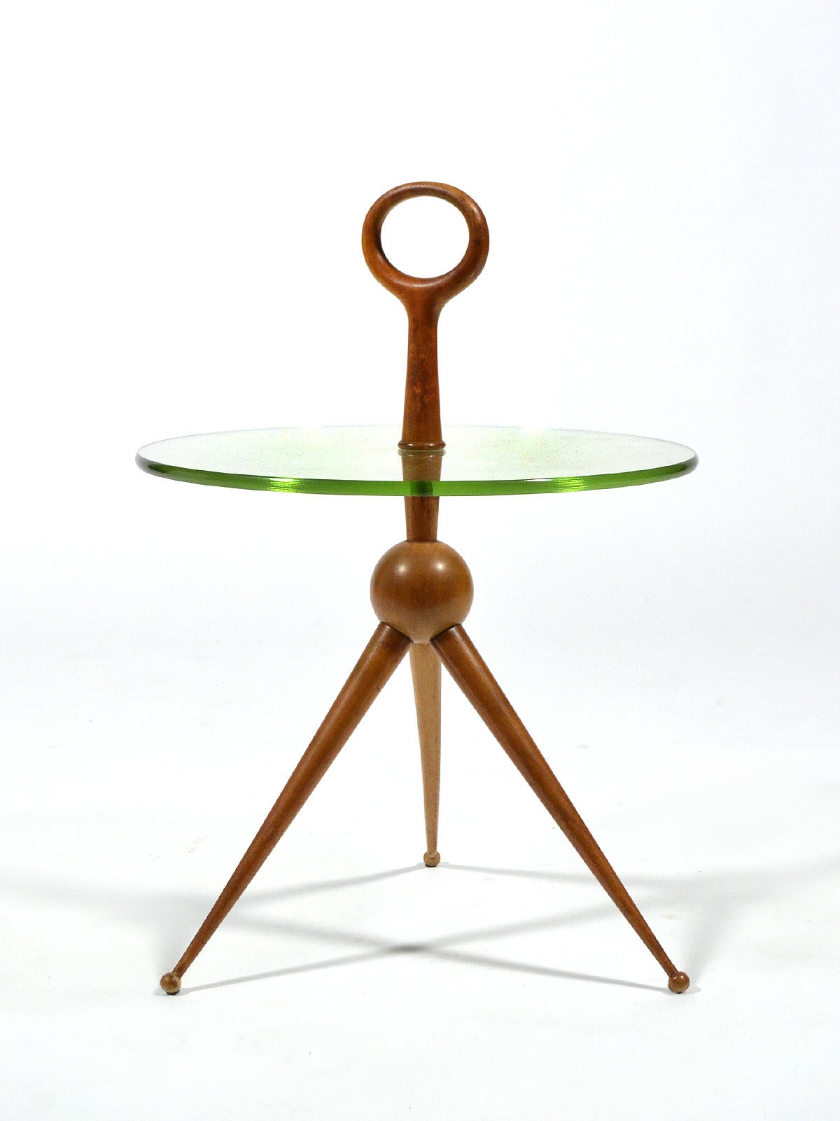 This beautiful little side table is just a perfect piece. A light, playful design with splayed legs connecting at the ball centre supporting a round pale green glass top. The scale and the integrated handle make it highly functional as well as