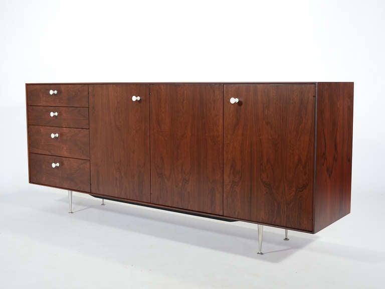 A spectacular design, the rosewood thin edge group is the most sophisticated and luxurious of the case-goods the Nelson office designed. This long credenza is perhaps the finest of the line. Low, lean, rich, and filled with useful components, the