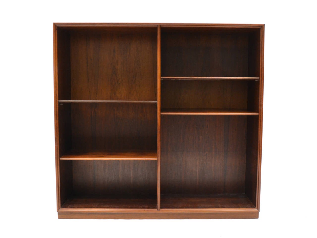 Beautiful and highly functional, this rosewood bookcase has two banks with four adjustable shelves. The case, which sits on a plinth base, has fluted edges giving it a delicate appearance, mitered corners, and an unusual extension of the top on the