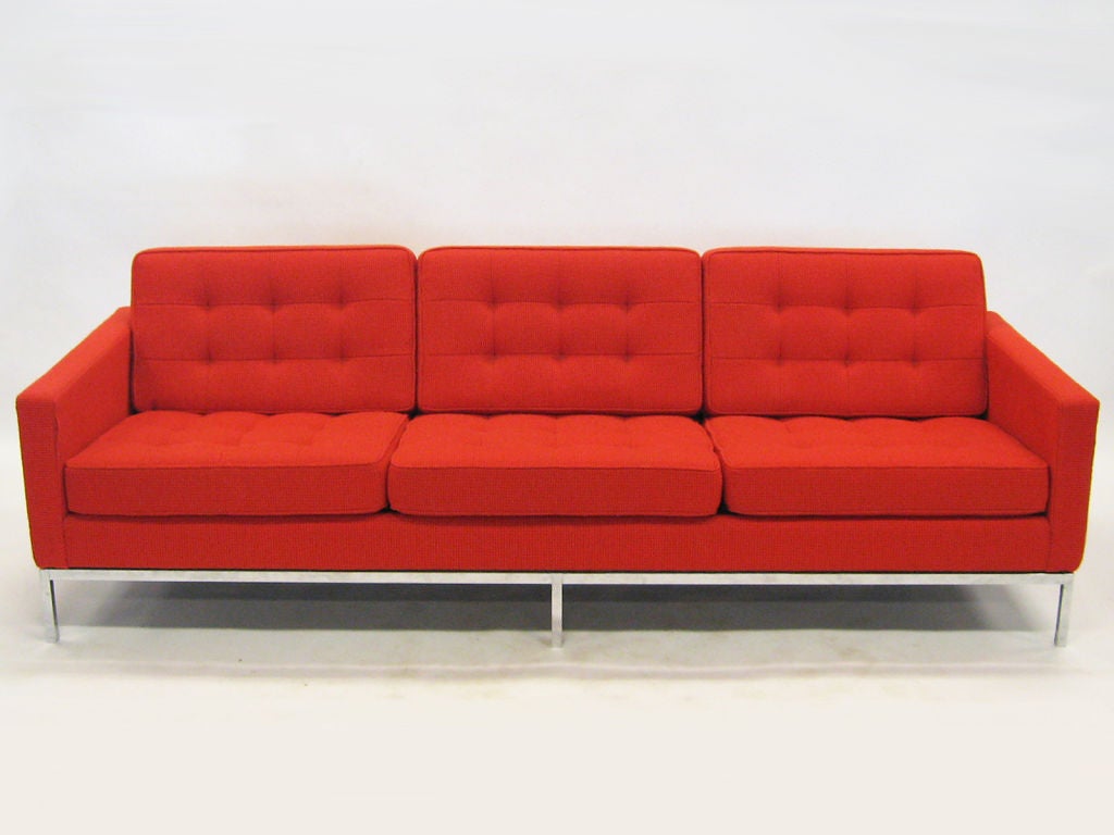 This classic Florence Knoll sofa is as comfortable as it is handsome. Recently upholstered in fire red Cato fabric, this early example has design features which have since been eliminated by Knoll. The sofa has the subtle reveal between the base and
