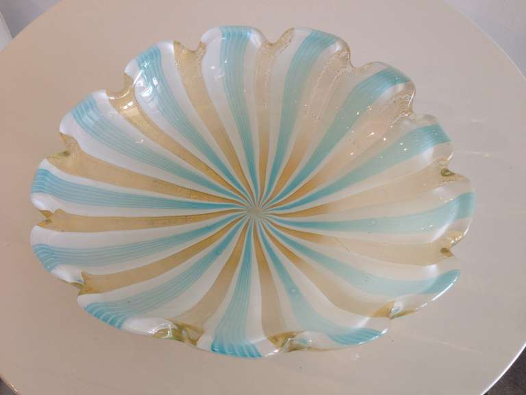 Hand blown blue, white, and gold glass with stripes and swirls.