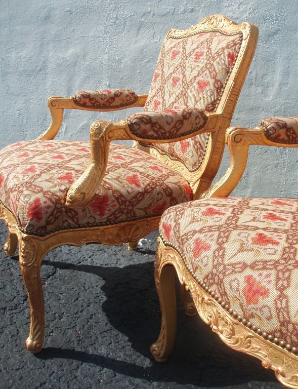 Set of four (4) Regence style decoratively carved and parcel-gilt finished fauteuils, upholstered in red floral and brown lattice designed fabric with nailhead trim