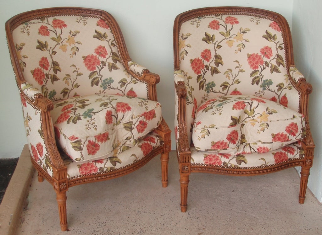 Handsome pair of Louis XVI style carved bergeres with lampas upholstery, nailhead trim, and down-filled seat cushions.