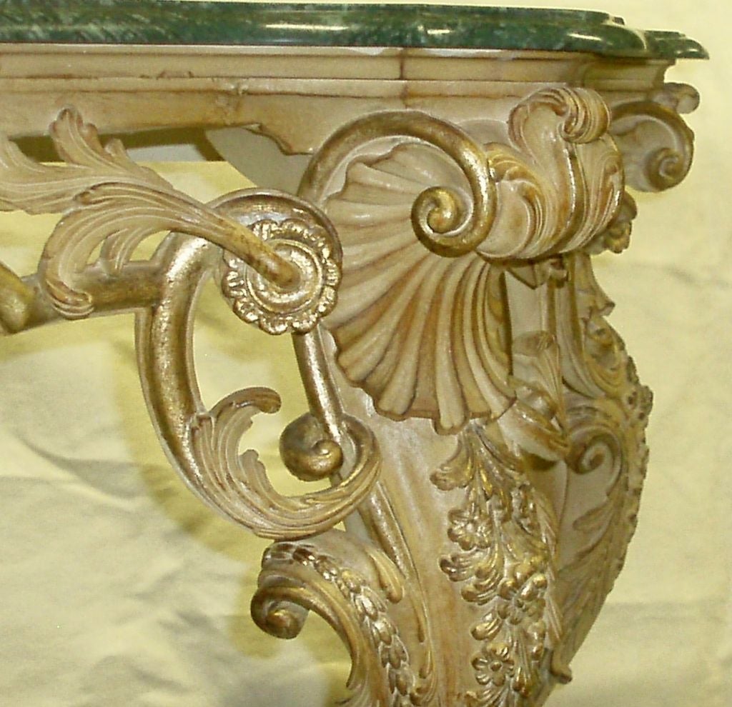 Regence style ornately carved four-legged console with Verde marble top resting on bleached wood base with gilded detailing, intricately carved design with shell motif corners, cabriole legs terminating in rosettes, circa 20th century.
