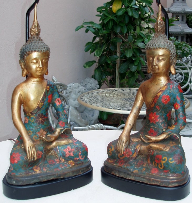 Charming Pair of Matched Bronze Buddha Figures Seated in Lotus Position, Wearing Colorful Hand Applied Cloisonne Robes Decorated with Floral Designs, Mounted as Lamps on Black Finished Wood Bases with Stem Mounts behind